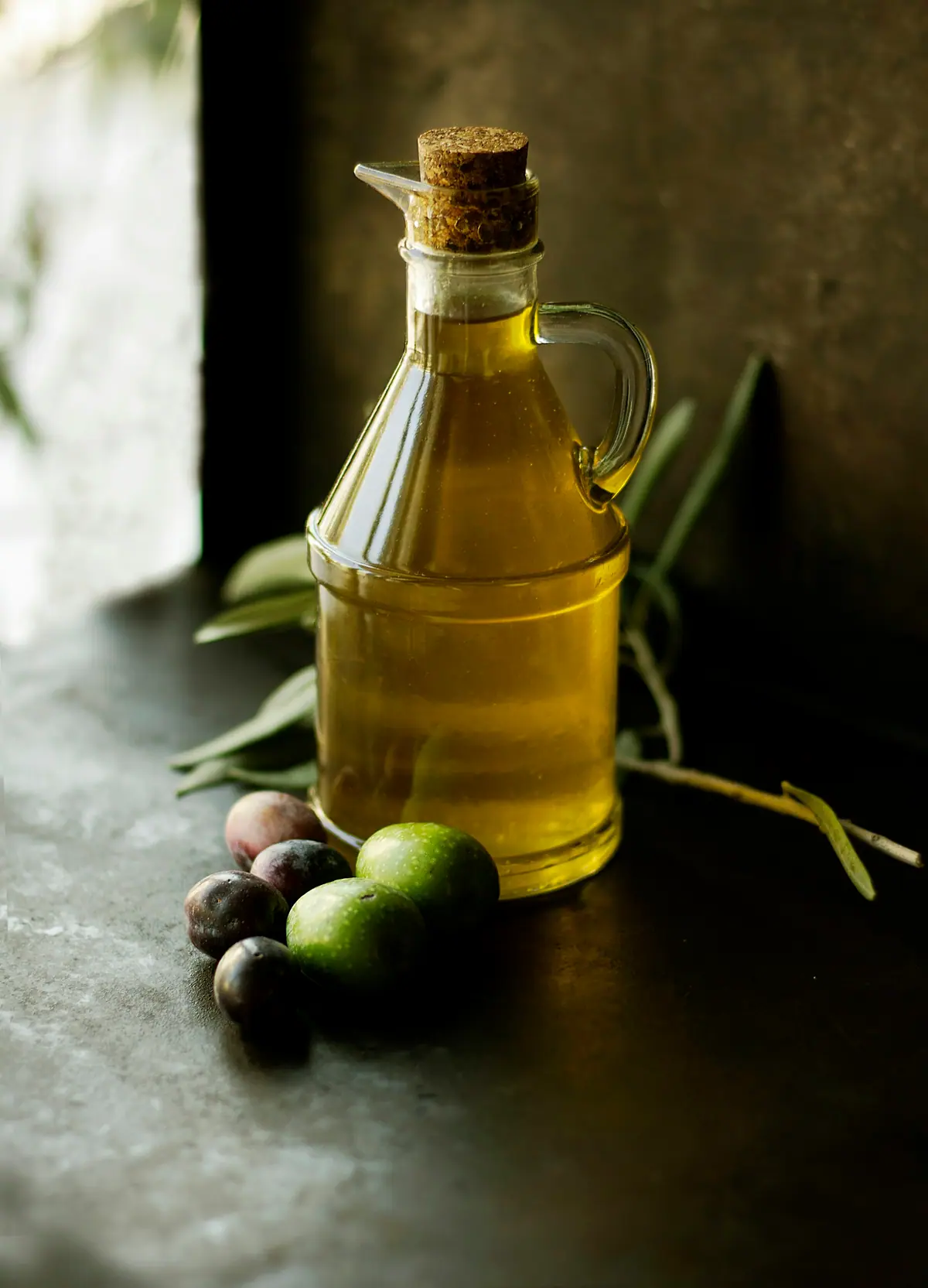 Zeytin taneleri yanında zeytinyağı dolu cam şişe